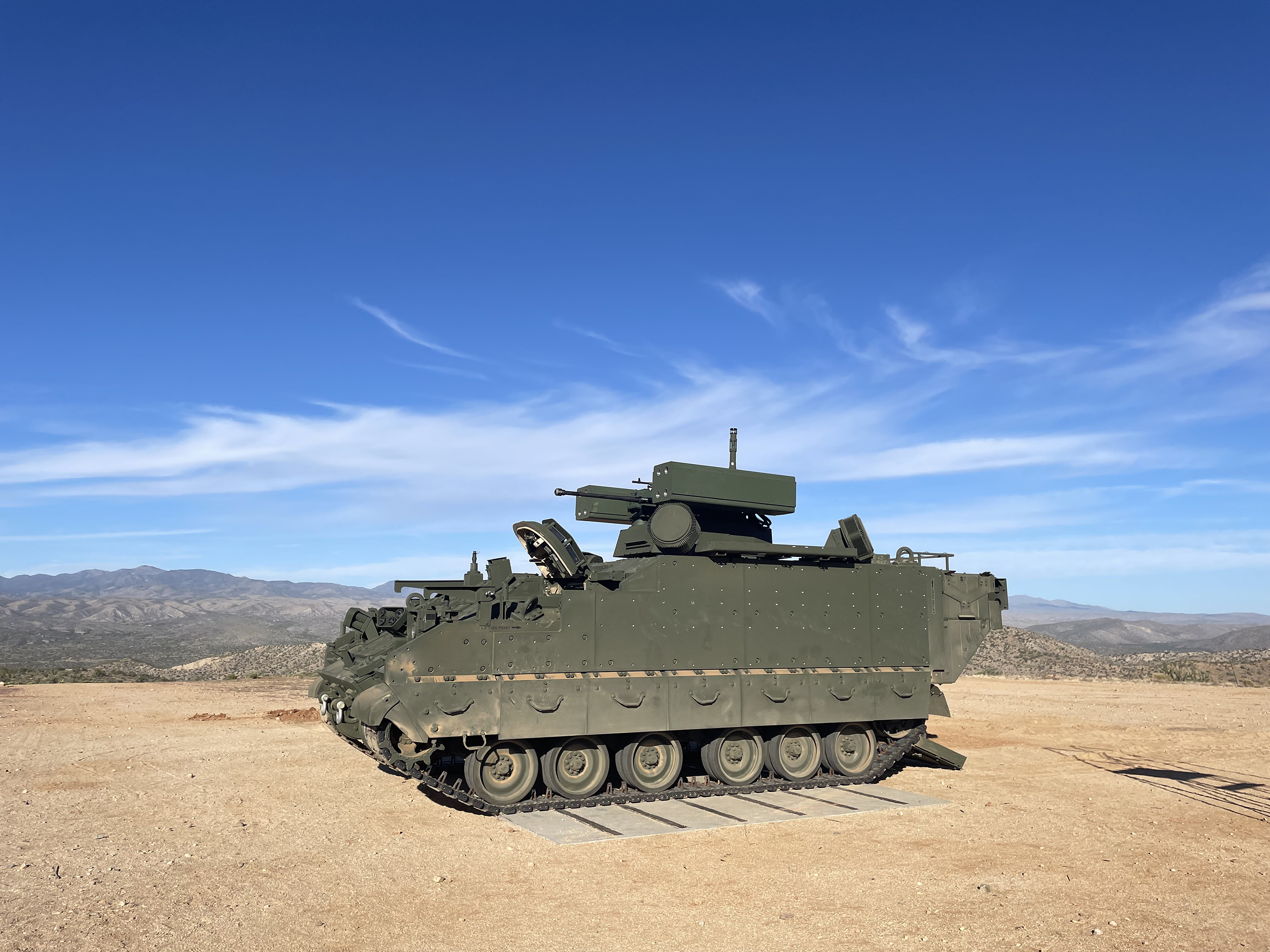 BAE Systems’ green Armored Multi-Purpose Vehicle (AMPV) Counter-Unmanned Aircraft System (C-UAS) prototype with desert mountain range in the background.